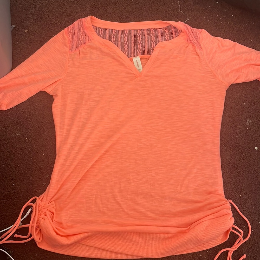 Short sleeve coral top with a lace square part on the back of it.